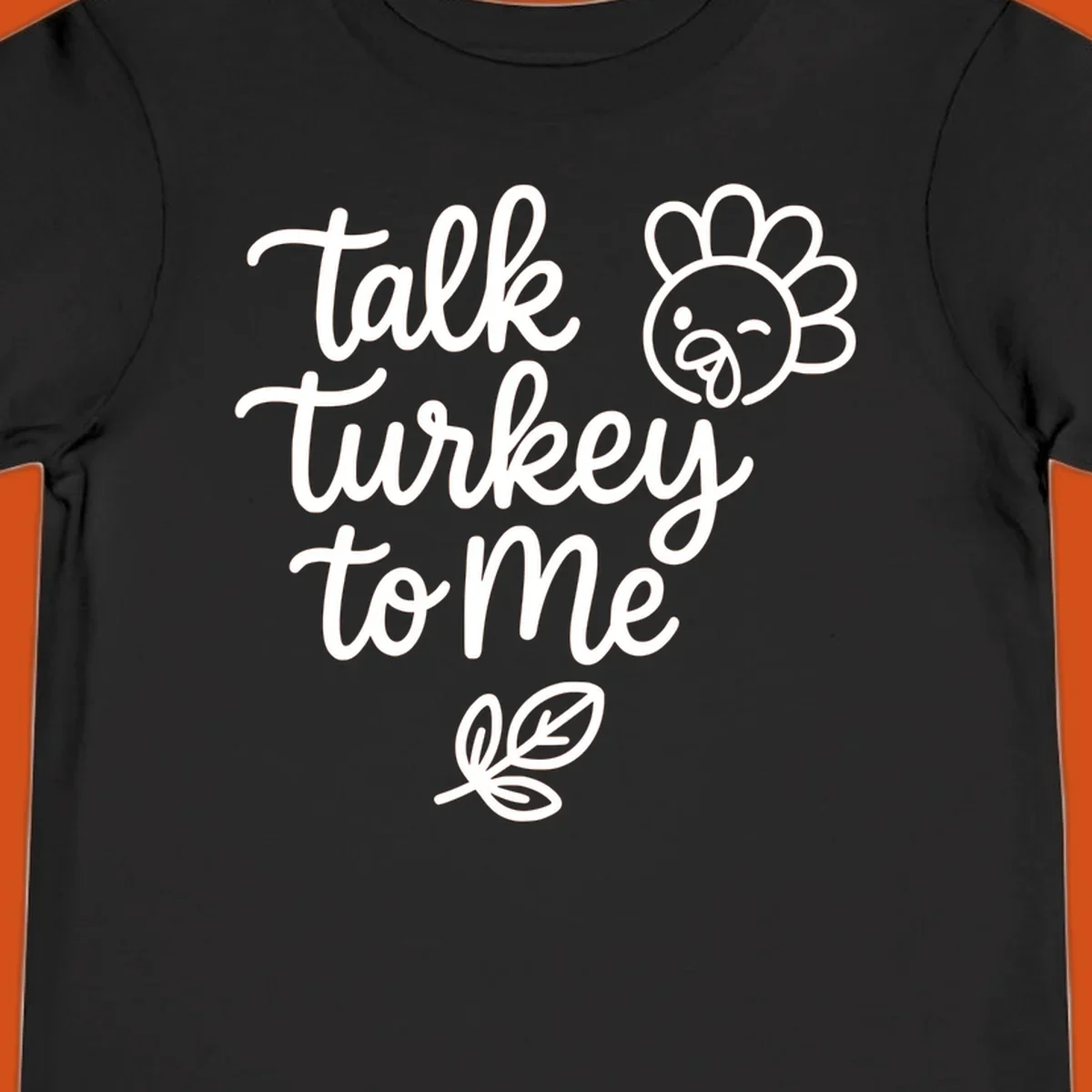 Talk Turkey To Me Thanksgiving phrase with cartoon turkey and leaf illustration.