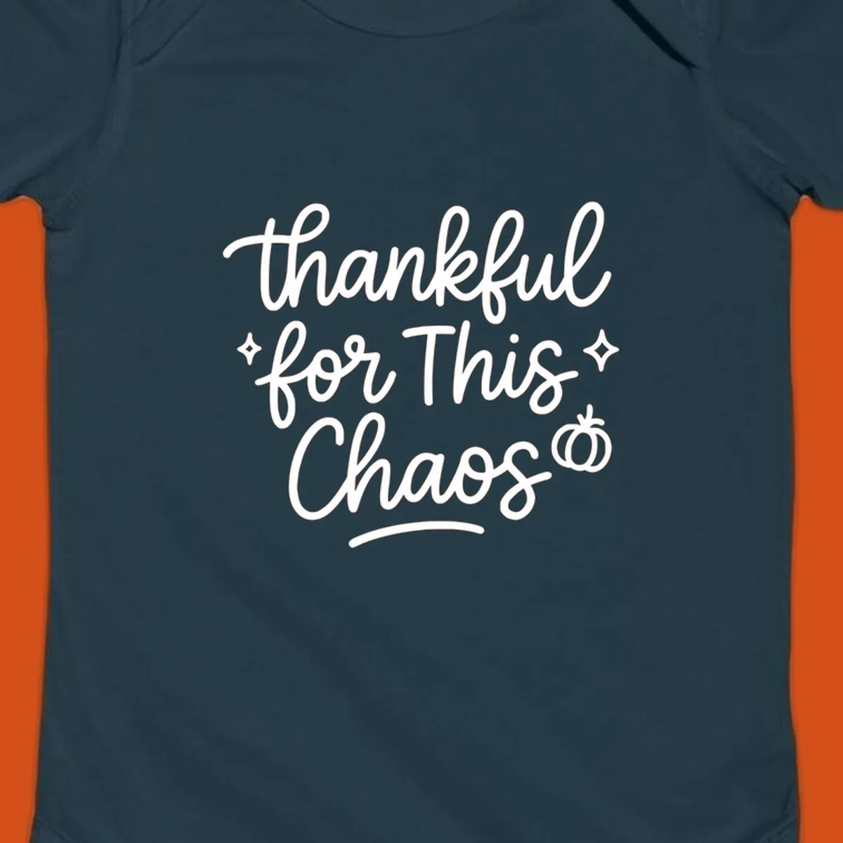 White script text 'thankful for This Chaos' with sparkles and a pumpkin on a black background.