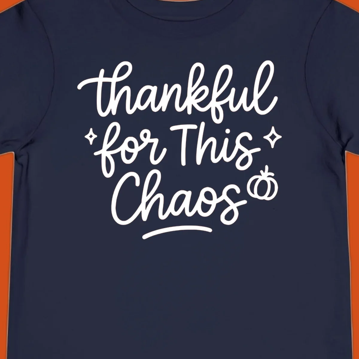 White script text 'thankful for This Chaos' with sparkles and a pumpkin on a black background.