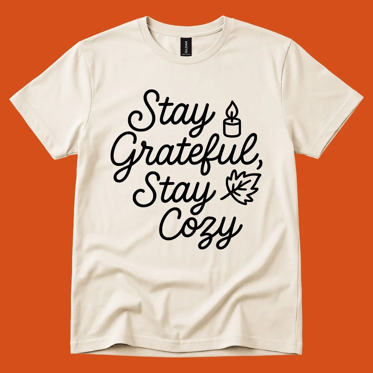 Text design with 'Stay Grateful, Stay Cozy' phrase, candle, and leaf for grateful-cozy-fall theme.