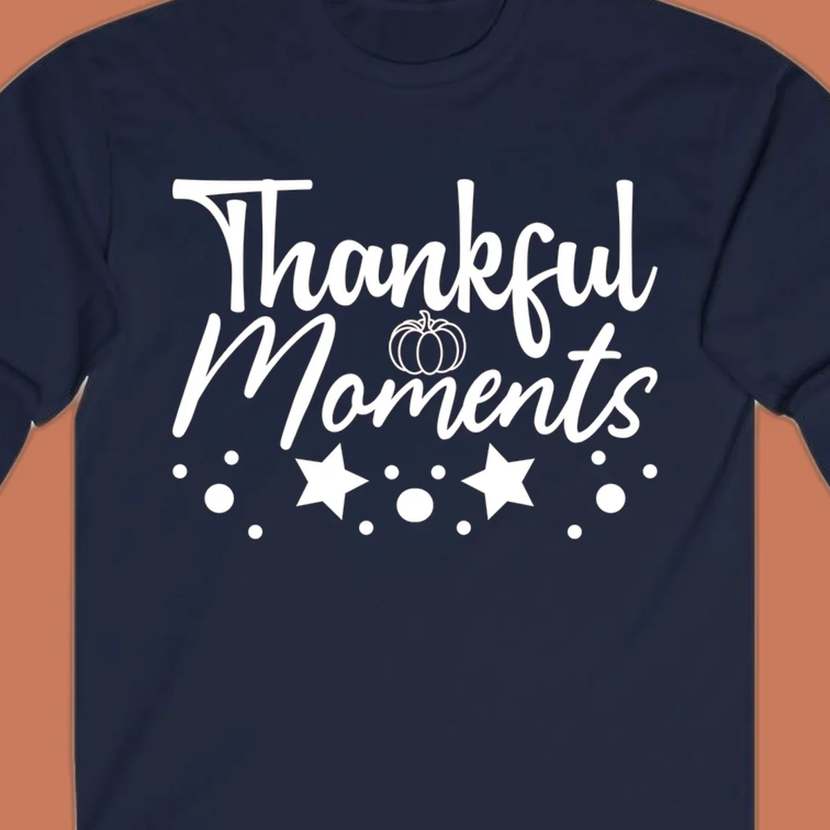 Thankful Moments autumn script text with pumpkin, stars, and dots graphic.