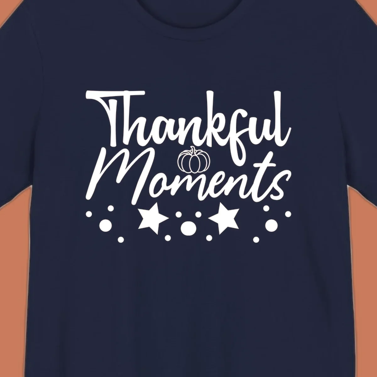 Thankful Moments autumn script text with pumpkin, stars, and dots graphic.