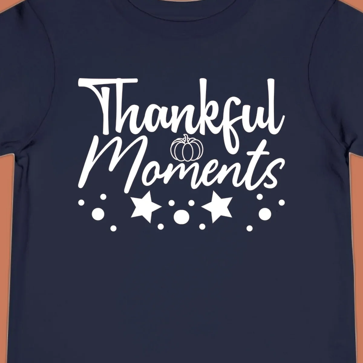 Thankful Moments autumn script text with pumpkin, stars, and dots graphic.