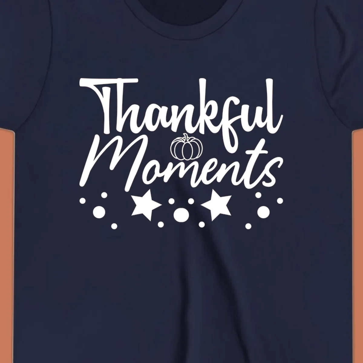 Thankful Moments autumn script text with pumpkin, stars, and dots graphic.