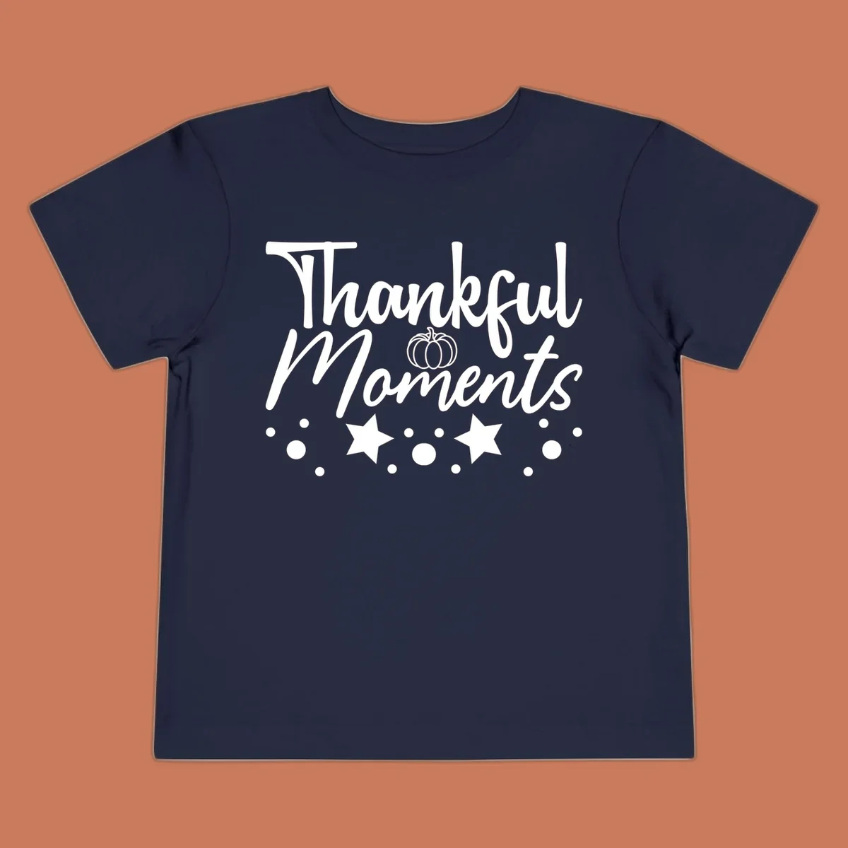 Thankful Moments autumn script text with pumpkin, stars, and dots graphic.
