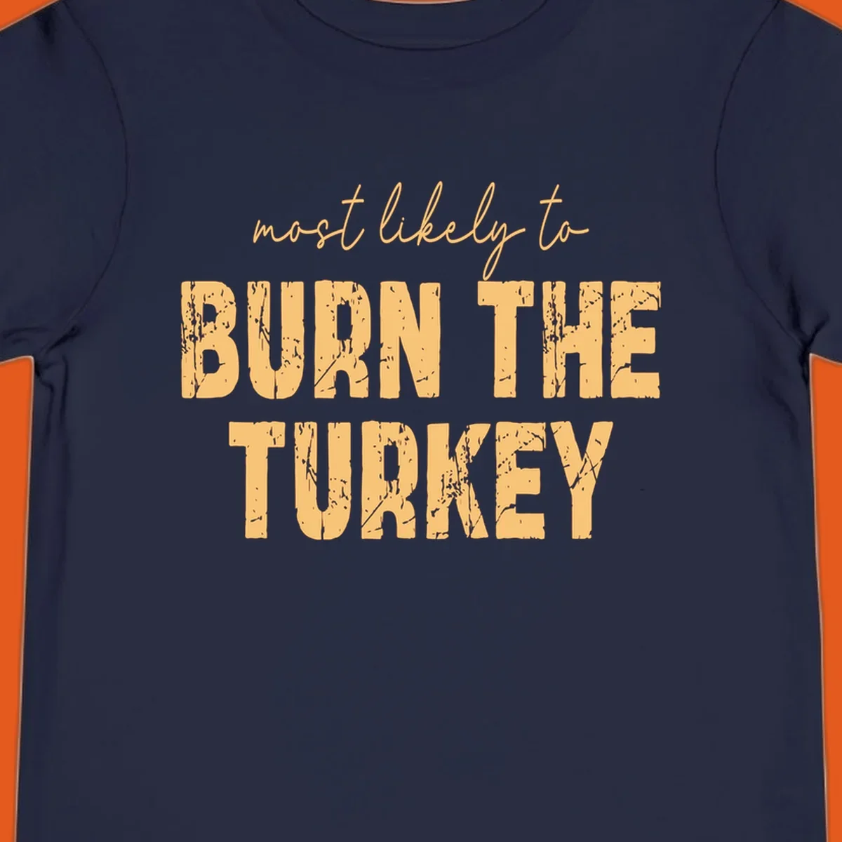 Most likely to burn the turkey text design in distressed orange and tan.