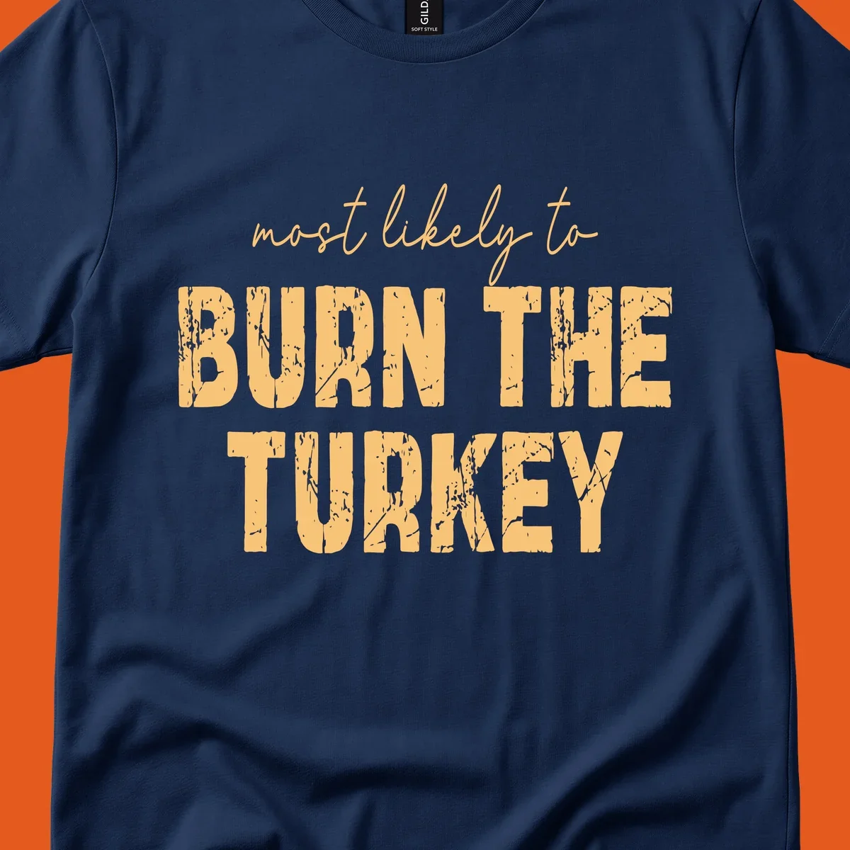 Most likely to burn the turkey text design in distressed orange and tan.