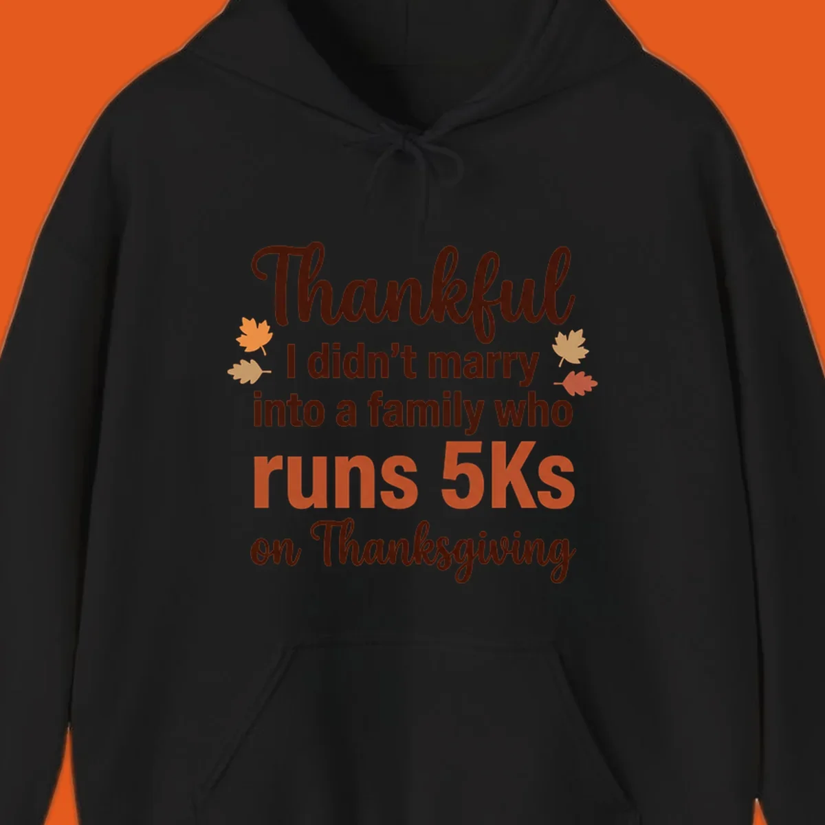 Text design 'Thankful I didn't marry into a family who runs 5Ks on Thanksgiving' with autumn leaves, for Thanksgiving 5k runner.