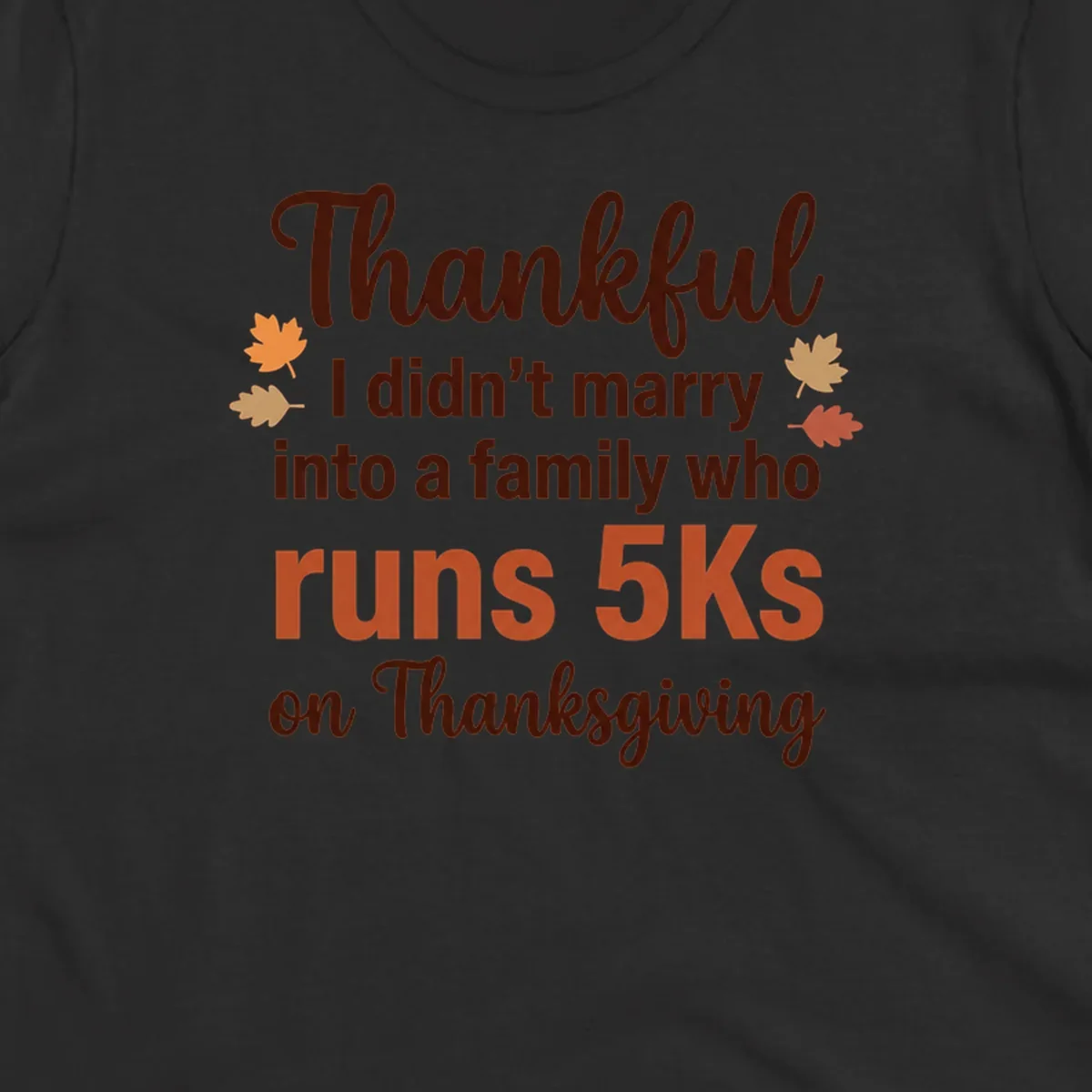 Text design 'Thankful I didn't marry into a family who runs 5Ks on Thanksgiving' with autumn leaves, for Thanksgiving 5k runner.