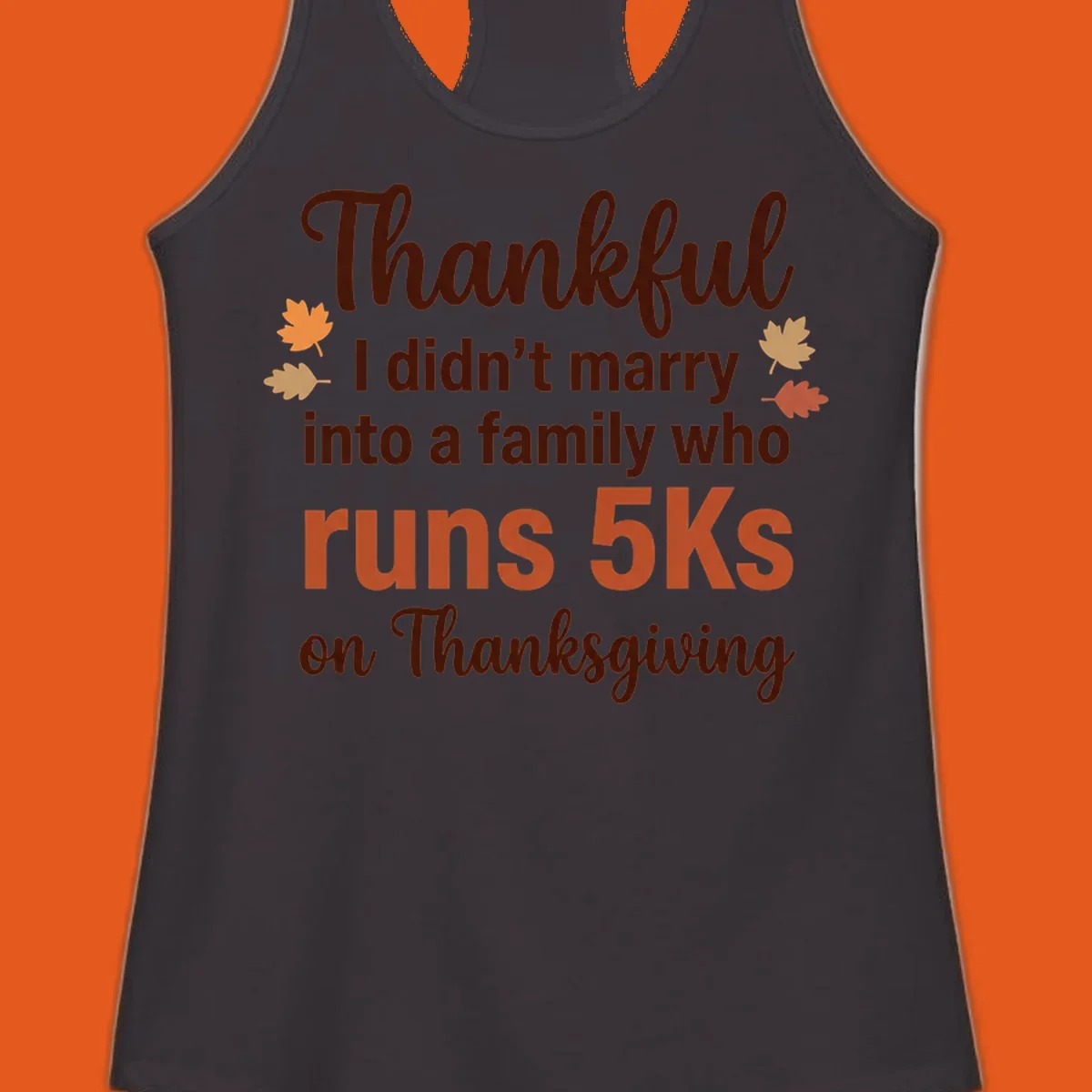 Text design 'Thankful I didn't marry into a family who runs 5Ks on Thanksgiving' with autumn leaves, for Thanksgiving 5k runner.