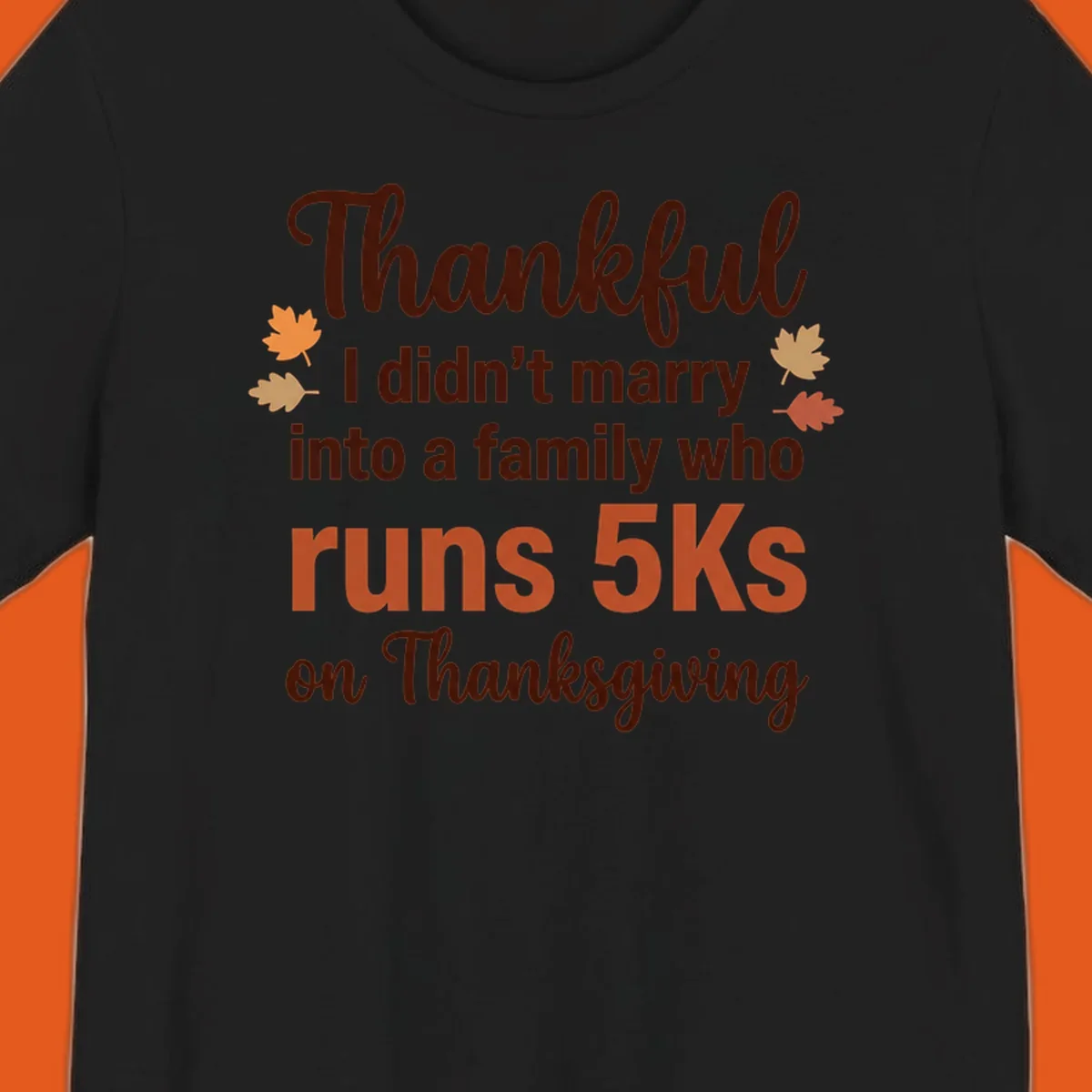 Text design 'Thankful I didn't marry into a family who runs 5Ks on Thanksgiving' with autumn leaves, for Thanksgiving 5k runner.