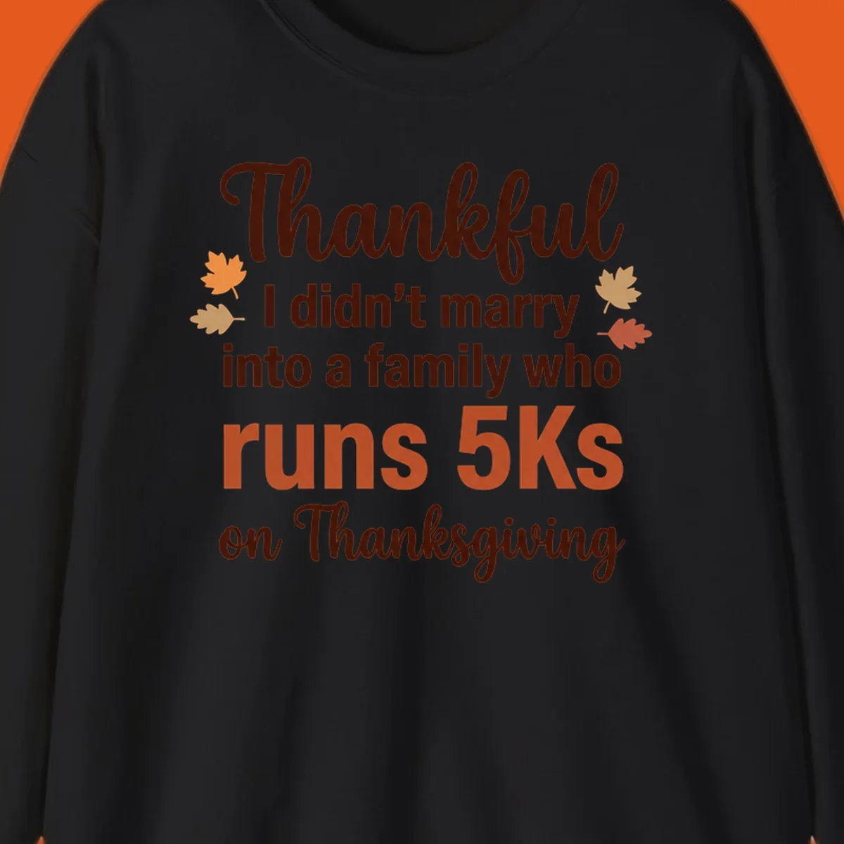 Text design 'Thankful I didn't marry into a family who runs 5Ks on Thanksgiving' with autumn leaves, for Thanksgiving 5k runner.