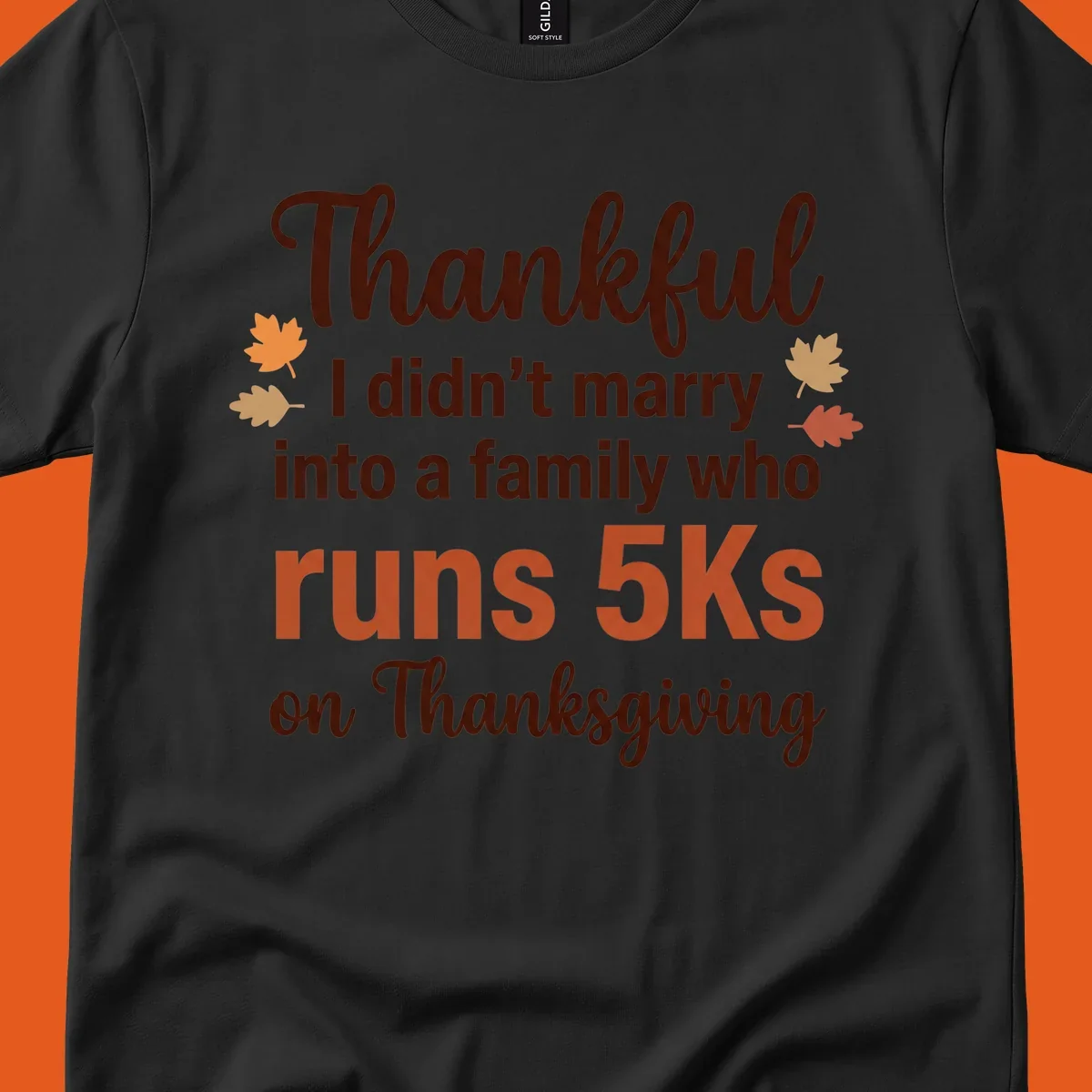 Text design 'Thankful I didn't marry into a family who runs 5Ks on Thanksgiving' with autumn leaves, for Thanksgiving 5k runner.