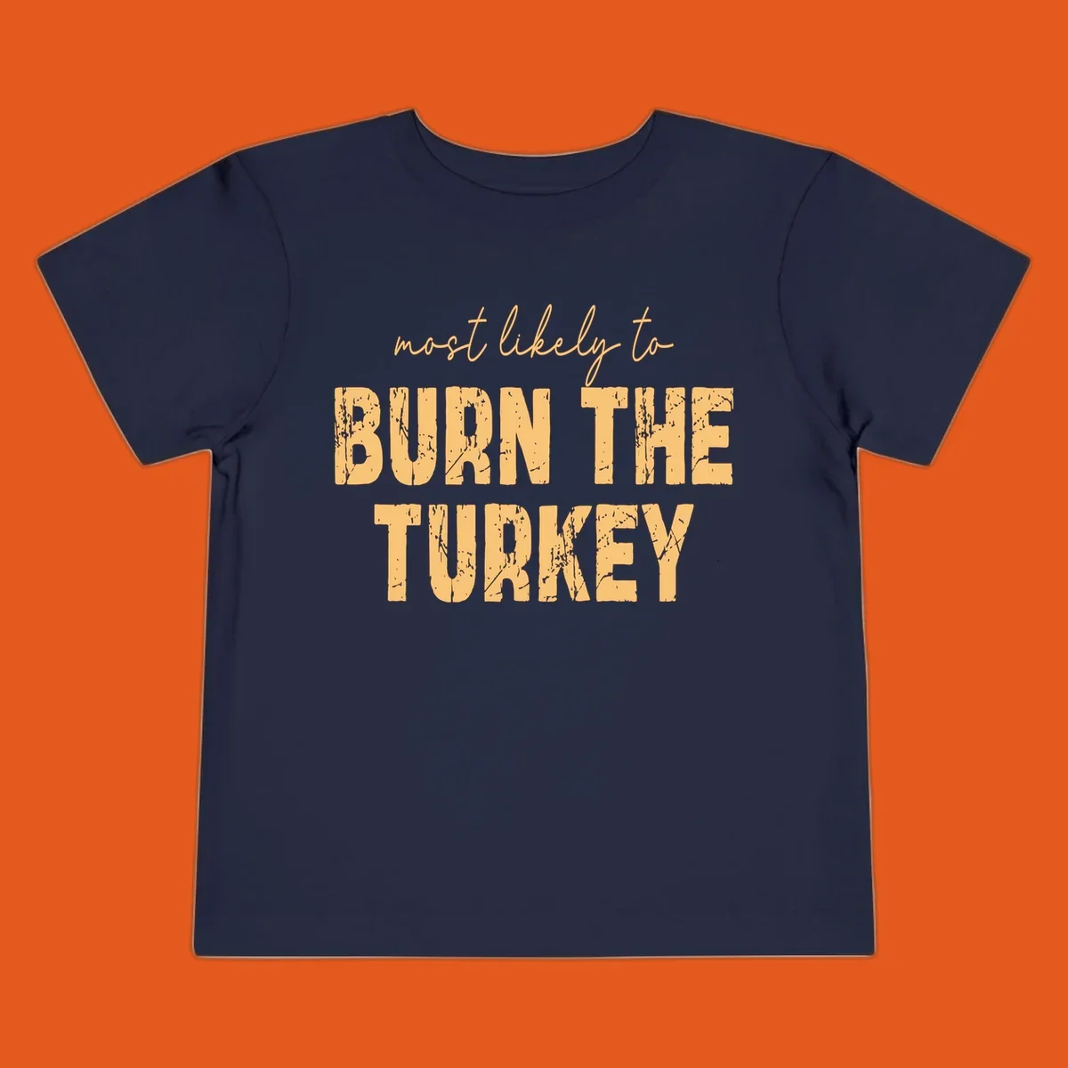 Most likely to burn the turkey text design in distressed orange and tan.