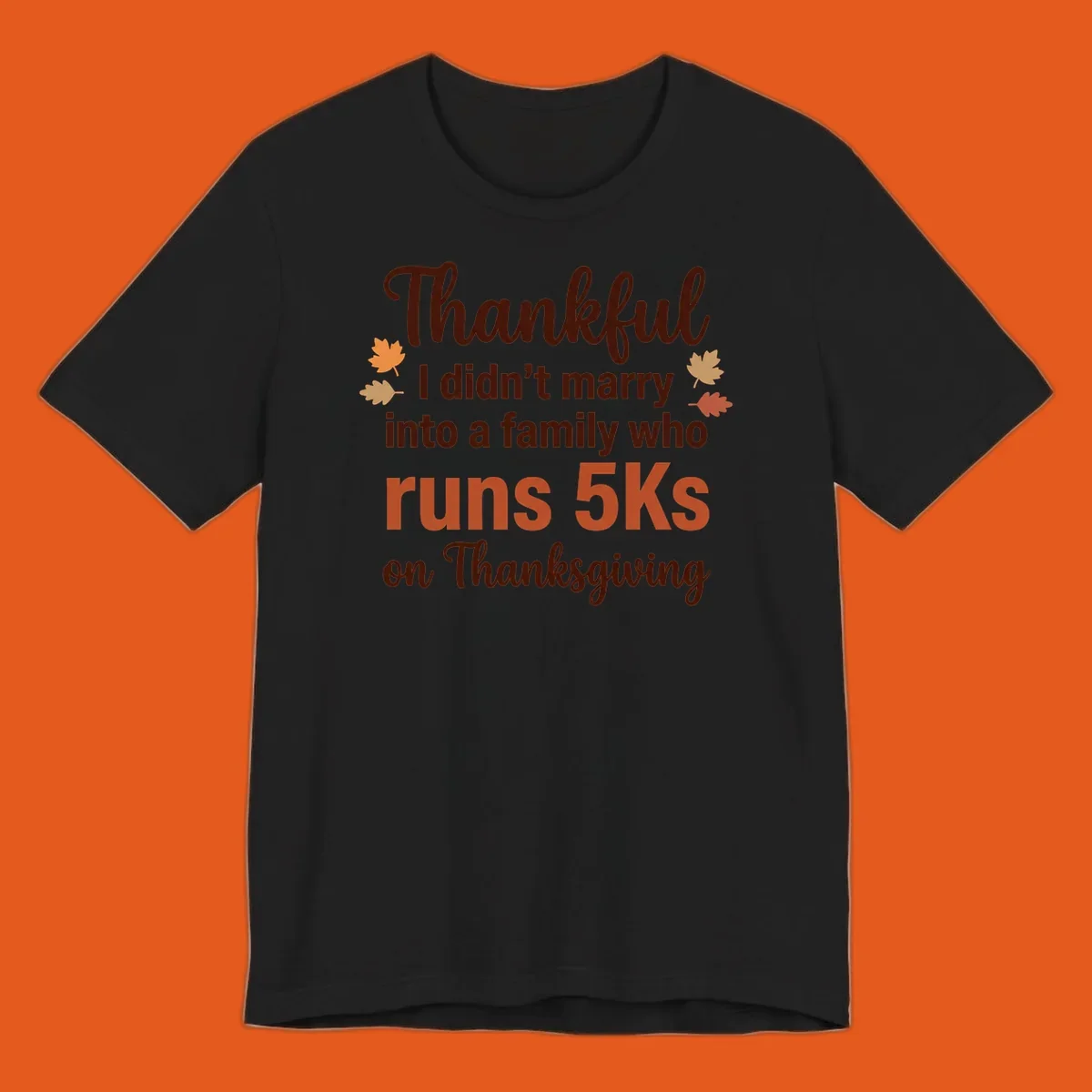 Text design 'Thankful I didn't marry into a family who runs 5Ks on Thanksgiving' with autumn leaves, for Thanksgiving 5k runner.