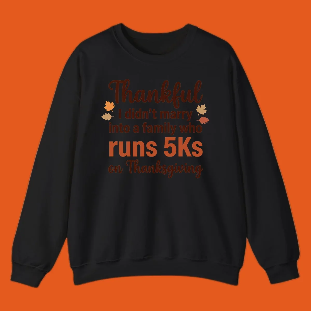Text design 'Thankful I didn't marry into a family who runs 5Ks on Thanksgiving' with autumn leaves, for Thanksgiving 5k runner.
