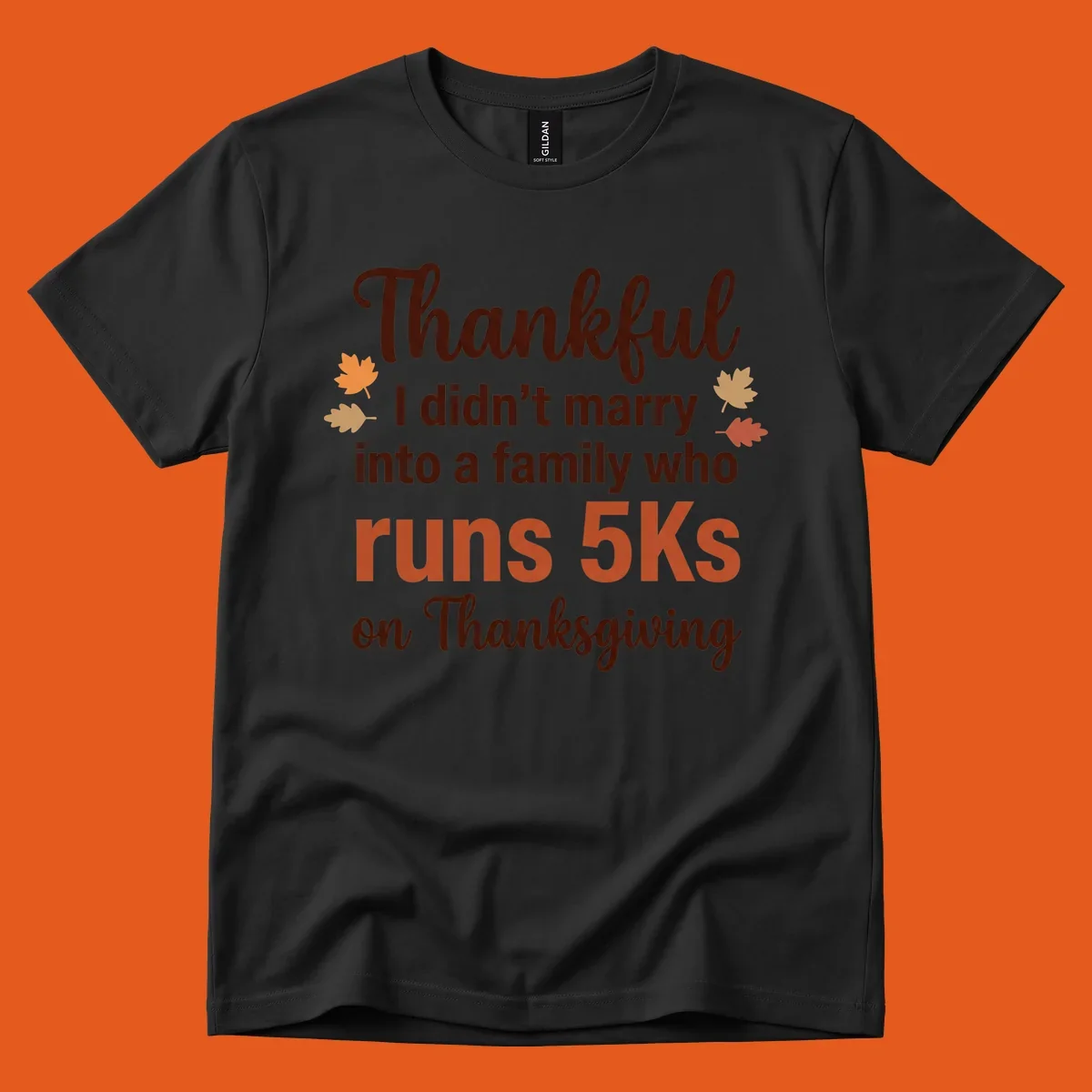 Text design 'Thankful I didn't marry into a family who runs 5Ks on Thanksgiving' with autumn leaves, for Thanksgiving 5k runner.