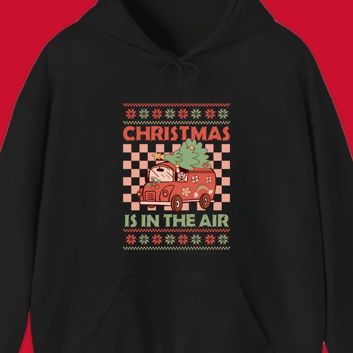 Christmas van with tree on top, text 'Christmas Is In The Air', snowflake borders, checkered pattern.